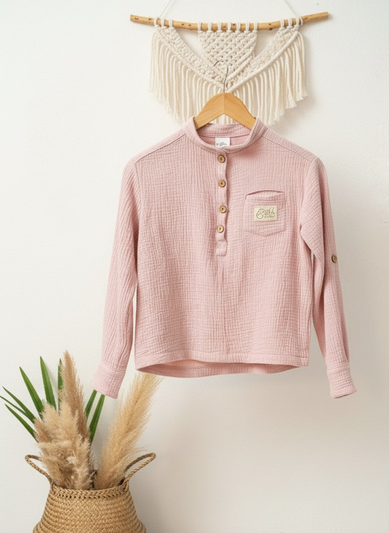 Rosa Musselinhemd mit Reverskragen an einer weißen Wand aufgehängt an einem Makramee