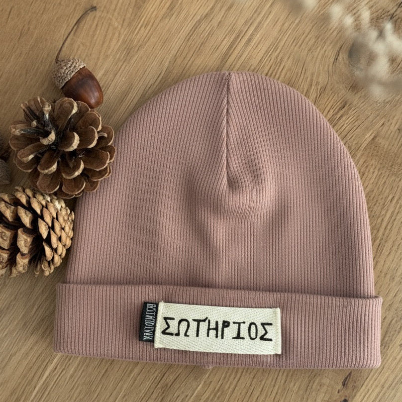 Gerippte Beanie Mütze mit Namen auf weißem Label und shcwarzen Weblabel "Best Kind ever" auf eineem Eicheholztisch daneben Tannenzapfen und Eicheln. Farbe der Mütze: Mauve.
